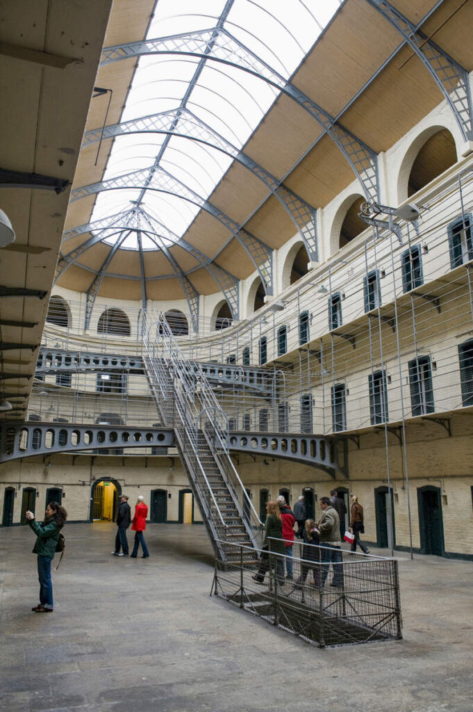 Kilamainham Gaol interior, one of the most haunted places in Dublin. The white walls have numerous wooden doors into the cells. There is a large stairs in the middle 