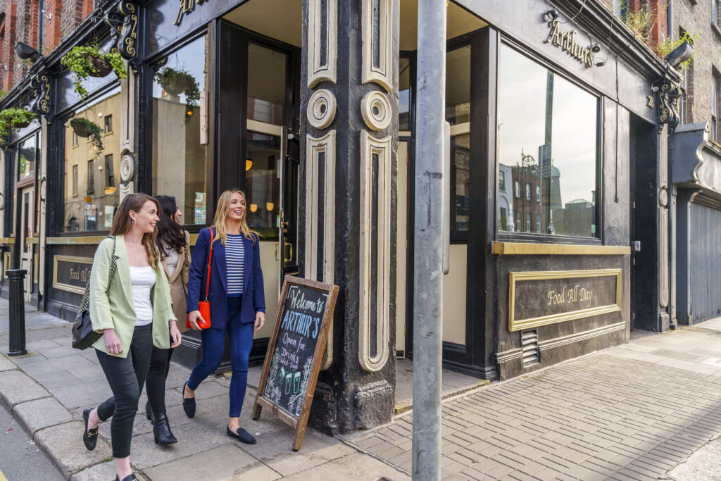Two women stand outside arthur's jazz & blues pub on thomas street.