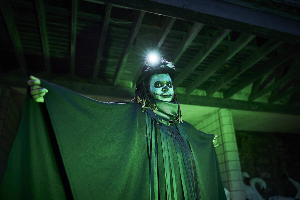 A man in a skeleton mask is illuminated by an emerald green mask at a Halloween Event in Dublin